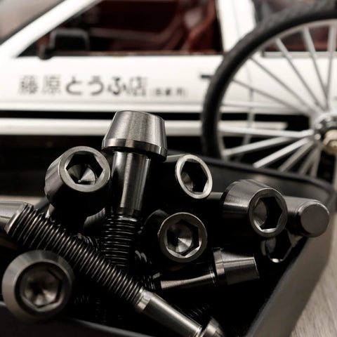 Titanium M4 Socket Head Cap Screws Set For Bike Stem 6Al4V Grade 5 Lightweight Bolts scattered in front of a bike wheel