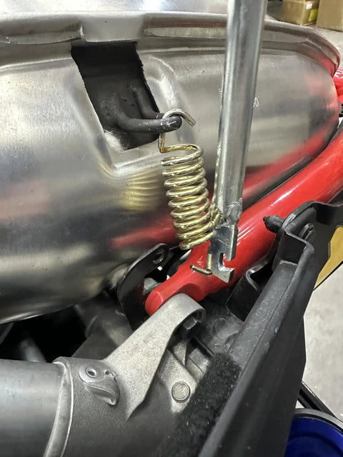 Exhaust Spring Removal Tool For Snowmobiles And Motorcycles Pull Push Twist in use, removing a spring from a metal engine part.
