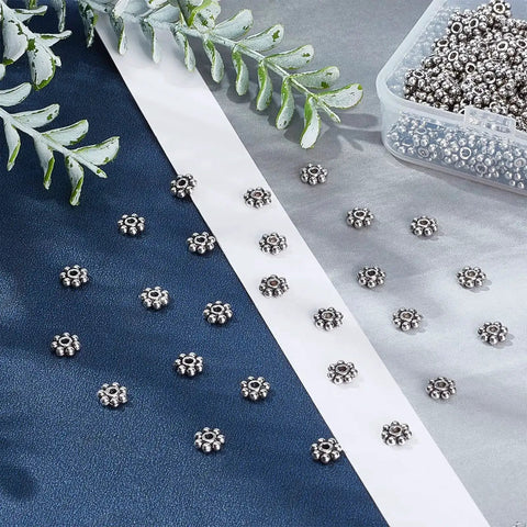 Assorted Antique Silver Daisy Flower Spacer Beads 6mm, 300Pcs Tibetan Style for DIY Jewelry Crafting on fabric background