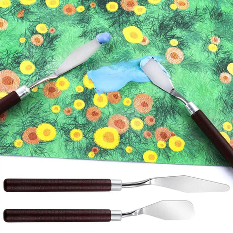 Palette knives spreading blue paint on colorful floral canvas with two additional knives below