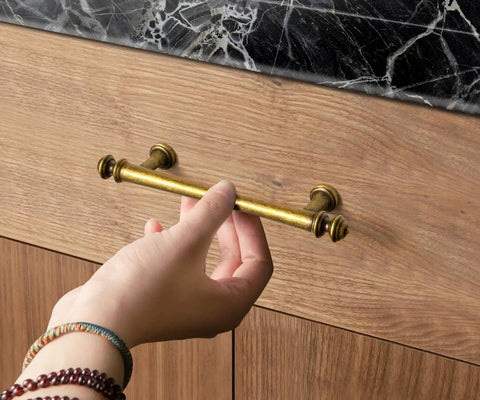 Hand reaching for Six Pack 3 Inch Hole Center Cabinet Pulls Antique Brass Zinc Alloy Drawer Handles for kitchen cabinets