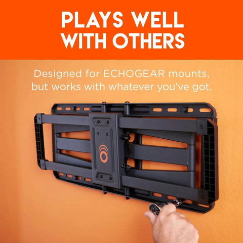 Wall-mounted TV bracket with a person's hand adjusting the bracket. Compatible with various mounts, shown on an orange wall.