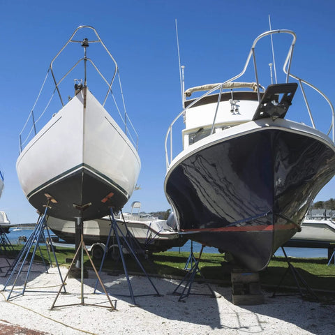 Two boats on stands in a marina, showcasing areas ideal for Dockside Ready Marine Grade Lubricant And Penetrating Oil For Boats And Gear.