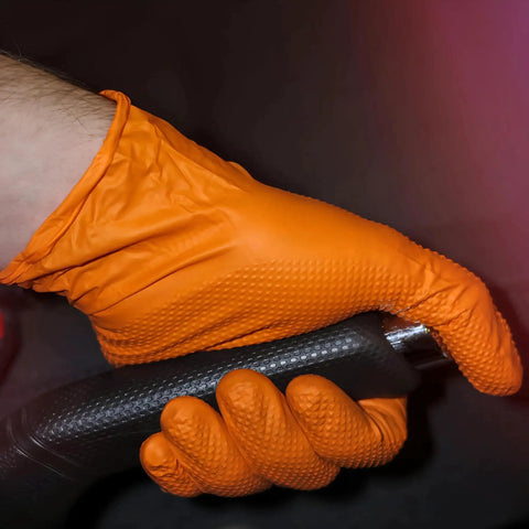 Hand wearing Heavy Duty Nitrile Gloves 8 Mil Diamond Grip Latex Free Orange XXL 100 Count holding a black tool handle
