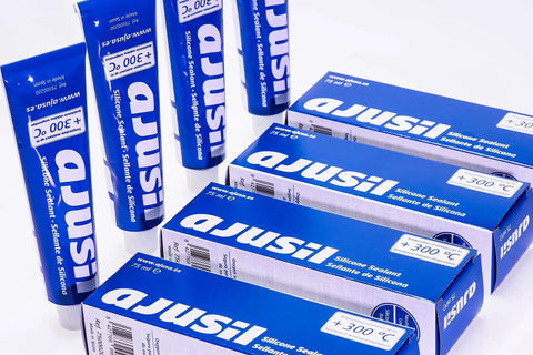 Boxes and tubes of Ajusil silicone sealant, suitable for high-temperature use, displayed on a white background.