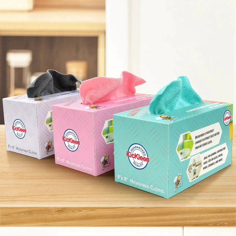 Three boxes of 8x8 inch microfiber cloths in different colors placed on a wooden counter.