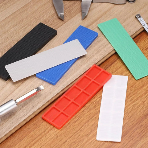 Assorted colored 20 Pcs Plastic Flat Shims For Leveling 3mm Structural Tile Shims on a wooden surface.