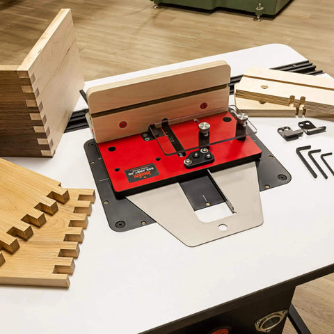 Pro Grade Box Joint Jig For Router Tables With Aluminum Indexing Keys And Smooth Bearing Glide System Includes One Quarter Inch, Three Eighths Inch, And One Half Inch Keys And Baltic Birch Fences For Precise Drawer And Box Joints set up on table with wood pieces