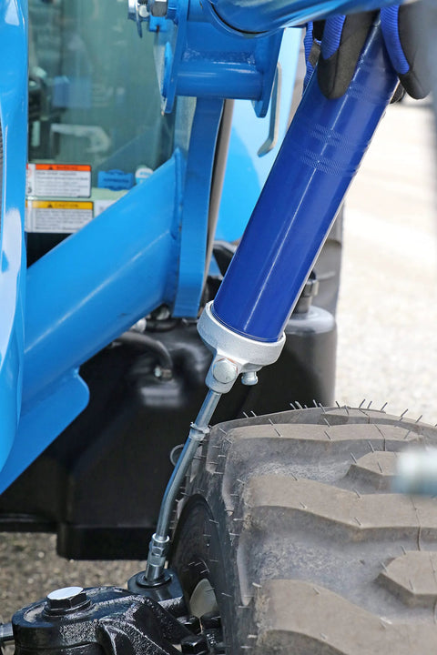 Lincoln 1142 lever-action grease gun, blue body with silver head, mounted near a tire; shows 6-inch extension and hydraulic coupler.