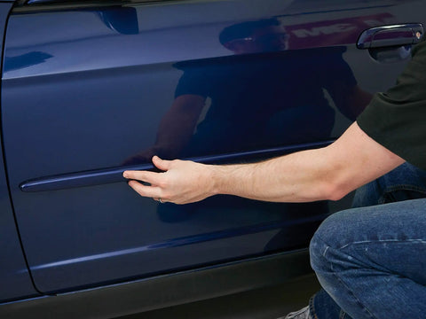 Applying Super Strength Automotive Tape 03609 - 1/2 in x 5 ft single roll to car side trim for secure bonding