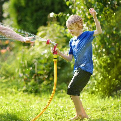 Solution4Patio yellow 5/8 in garden hose with red spray nozzle in use for yard watering