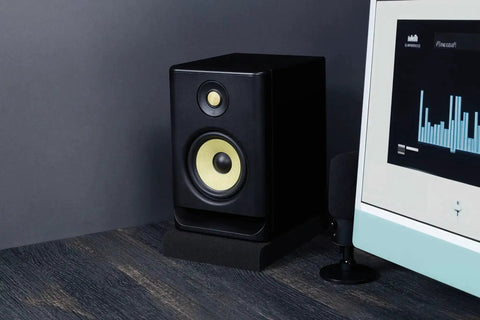Studio Monitor Isolation Pads For 5 Inch Monitors, 2 Pack, High Density Acoustic Foam supporting a speaker beside a computer screen.