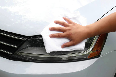 Hand using Bulk T Shirt Rags 5 Lb Box White Cotton Wiping Cloths For Paint, Stain, Grease Cleanup In Shop And Auto Use on car headlight