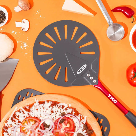Pro Grade 9 Inch Perforated Pizza Peel With Extendable 27 To 41 Inch Handle For Indoor And Outdoor Ovens, Lightweight Aluminum Turning Peel, Nonstick Metal Pizza Turner Red TKC on orange background with ingredients