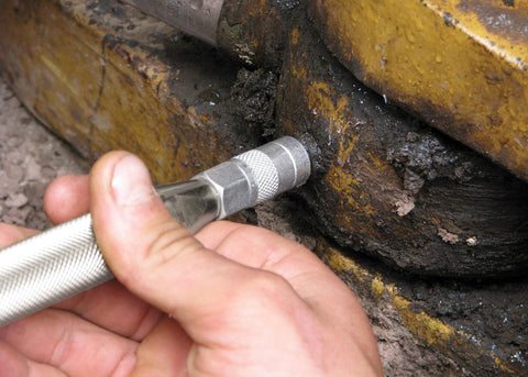 Grease joint rejuvenator kit tool in hand, steel with knurled grip, used on a rusted automotive shaft joint