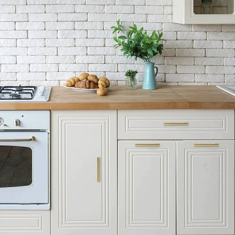 White kitchen with stainless steel oven, wood countertop, and cabinets, featuring matte black pulls for upgraded kitchen cabinetry.