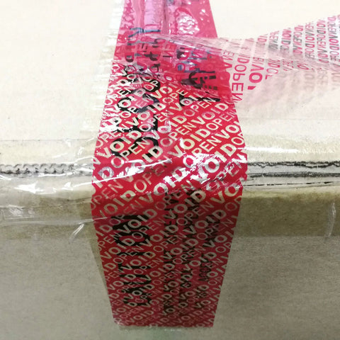 Tamper-evident packing tape on cardboard box; red tape with white VOID pattern.