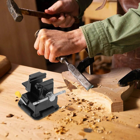 Mini Bench Vise Clamp With Suction Base For Jewelry Making And Woodworking, compact and lightweight, on a wooden tabletop with carving tools.