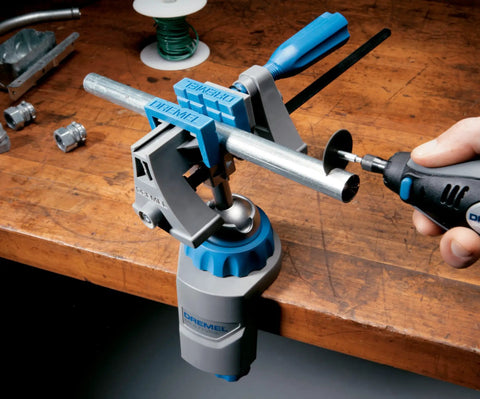 3 in 1 Multi Vise Attachment for Dremel Rotary Tool, mounted on workbench, holding metal pipe with 360-degree rotation, in use