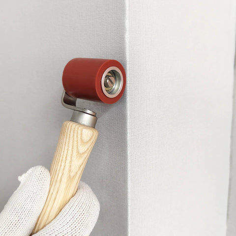 Welding handheld roller with red silicone wheel and wooden handle.