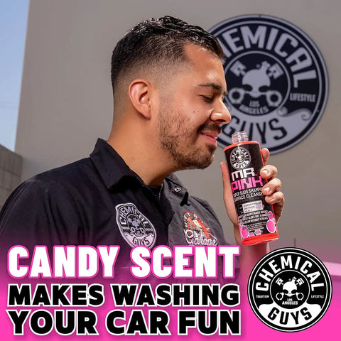 Man holding Mr Pink Foaming Car Wash Soap for Foam Cannons and Buckets Candy Scent, 473 ml, outdoors with Chemical Guys logo.