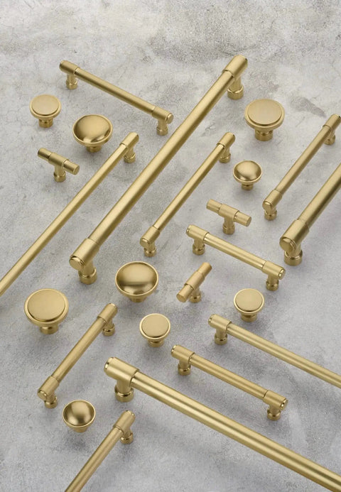 Various Emtek Jasper 5 Inch Center To Center Bar Cabinet Pulls 86688US4 in brass finish from the Industrial Modern Collection displayed on concrete
