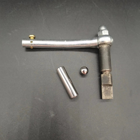 Top view of ZZRSDAN clutch repair kit components: curved silver lever, cylindrical steel rod, small ball, and square-ended shaft