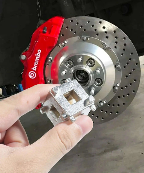Person holding Brake Caliper Piston Tool for Rear Disc Brakes in front of car's rear disc brake system.