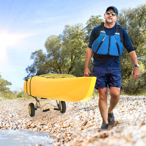 Man transporting yellow kayak on Go-To Universal Kayak Carrier Trolley For Kayaks Canoes Paddleboards Float Mats And Jon Boats With 200-Pound Capacity, Solid Airless Tires, Anodized Aluminum Frame, Easy Handle, And Two Ratchet Straps along rocky shore.