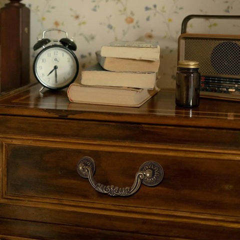 Six Pack Antique Brass Drawer Pulls With Four And Three Quarters Inch Hole Centers on wooden cabinet scene with books and clock
