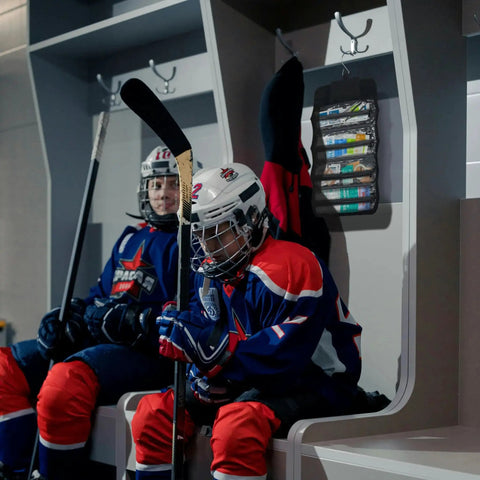 Hockey players in locker room with Ready To Go 73 Piece Coaches And Team Sports First Aid Kit In Roll Up Bag hanging on wall.