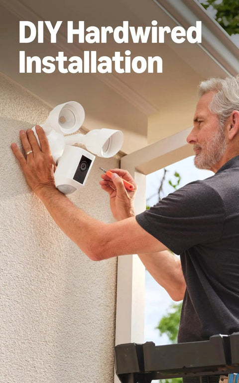 Man installing Floodlight Cam Wired Plus Outdoor Security Camera With 1080p HD And Motion Zones on house exterior