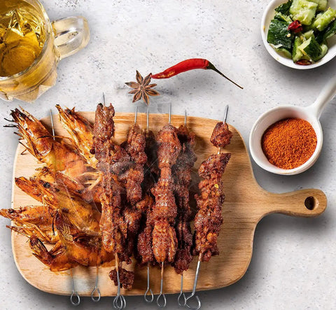 10 Inch Stainless Steel Square BBQ Skewers Set 12 Pack With Ring Tip Handles For Easy Grilling Grill Outs Kebabs Kabobs And Veggies Keeps Food From Spinning Durable Metal Skewers Great For Grilling At Home Or On The Go holding shrimp and meat on a wooden board with spices