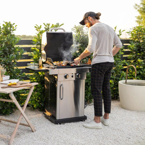 Gas grill outdoors; man grilling food on a stainless steel barbecue.