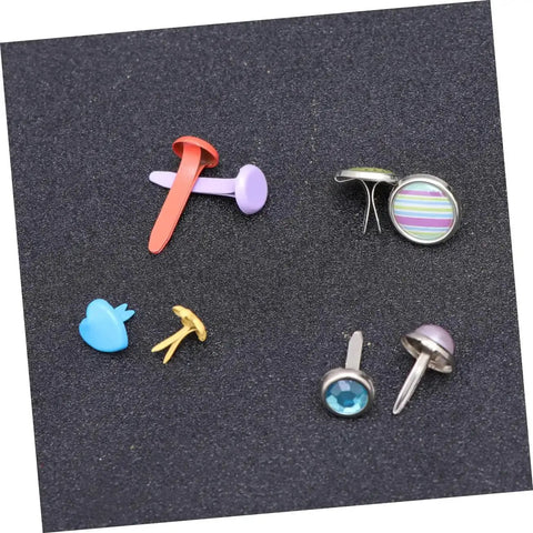 Assorted colorful metal brads with split pins on a black surface, part of 110 PCS Colorful Metal Brads Fasteners For Scrapbooking And Cardmaking.