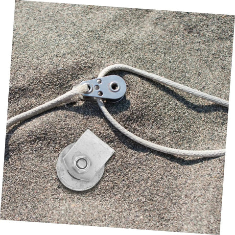 Metal pulley and rope system on sandy surface, showcasing components used in industrial cast iron groove wheel garage door roller setups.
