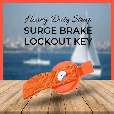 Orange surge brake lockout key with heavy-duty strap, front view on wooden deck