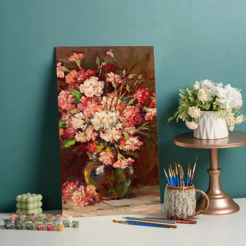 Painting of a vase with flowers next to art supplies and a vase on a table with blue background