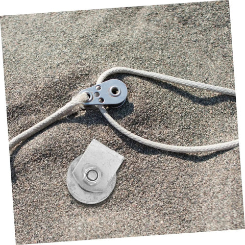 Cast Iron V-Groove Wheel Heavy Duty Steel Roller beside a rope on sandy ground, showcasing the wheel's durable design and utility.