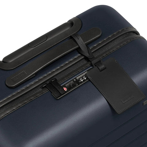 Close-up of Bigger Carry On Luggage From Away, showing TSA lock and durable navy polycarbonate shell.