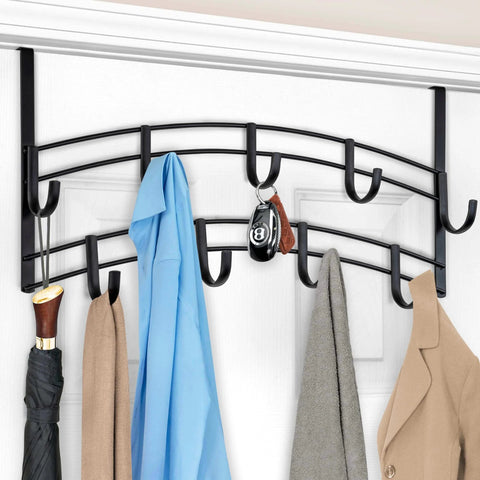 Over-the-door black metal coat rack with multiple hooks holding coats, a blue shirt, an umbrella, and a keychain on a white door.