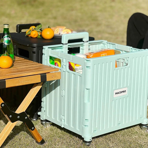 Green Macopro Foldable Utility Cart With Lid and Four 360 Degree Wheels next to a picnic table, loaded with grocery items.