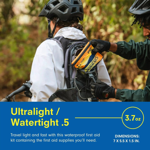Cyclist placing Ultralight Watertight First Aid Kit For Up To 2 People And 2 Days into backpack, ideal for hiking and biking adventures.
