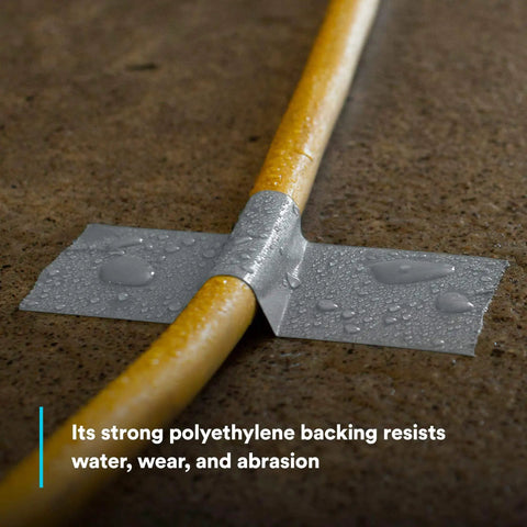 Extra Heavy Duty Duct Tape 6969, Silver, used on a yellow pipe, showcasing water resistance and abrasion resistance on concrete.