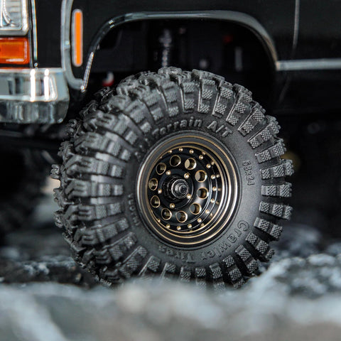 Close-up of Brass Beadlock Wheel Set With Black Coating And S5 1.0 Crawler Tires For Axial SCX24 AX24 TRX4M FCX24 Upgrades 1/24 1/18 RC Crawlers Negative Offset For Wider Stance Durable Bias Ply Build And Aggressive Side Lug installed on RC crawler with rugged tire tread.