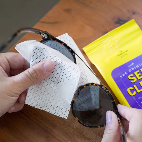 Person using Lens Cleaning Wipes For Glasses And Screens Streak Free Scratch Free 192 Wipes on sunglasses.