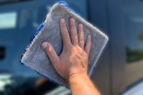 Person using Dual Side Microfiber Towel 8x8 Twist And Plush For Glass Cleaning Blue Gray to clean a car window.