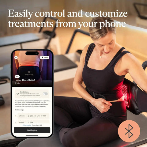 Woman using Four In One Back Wrap With Heat, Far Infrared, Vibration, And LED Therapy for epic lower back pain relief at home with phone app