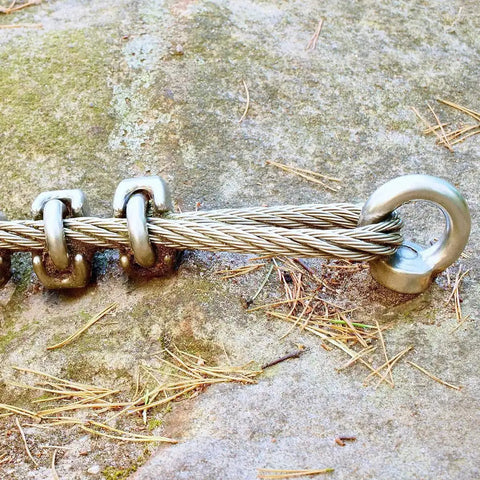 Close-up of a Ten Piece M6 Eye Bolts With Nuts Stainless Steel Lifting Eyebolts UNC in use on a wire rope for rigging applications.