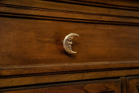 Drawer with a Set Of Six Gold Finish Cast Iron Crescent Moon Face Drawer Pulls For Celestial Decor installed on dark wood surface